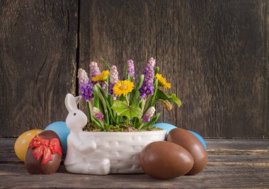 Paskalya kartı, tavşanlı kompozisyon, bahar çiçekleri ve ahşap zemin üzerinde çikolata yumurtaları, fotokopi alanı.