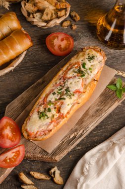 Ahşap bir zemin üzerinde peynirle ve domatesle doldurulmuş ekmek, malzemeler, fast food.