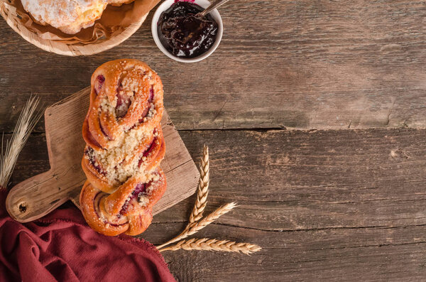 Fresh baked goods - delicious wicker bun stuffed with copy space on a wooden background