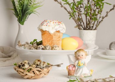 Easter cake and colorful eggs on a festive easter table with pussy willow and angel figurine