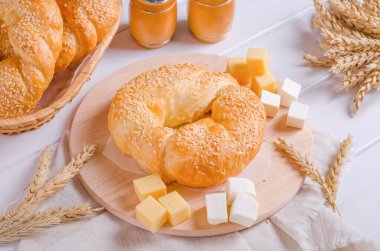 Beyaz ahşap arka planda yuvarlak ahşap bir tahtada peynirli taze çörek.