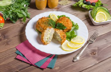 Koyu ahşap bir arka planda, beyaz bir tabakta yumurta ve otlarla doldurulmuş kızarmış et pirzolası.
