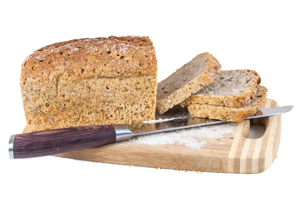 Skära fullkornsbröd och kniv på en skärbräda — Stockfoto