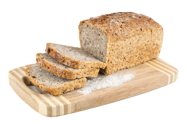 Corte pão integral em uma tábua de cortar — Fotografia de Stock