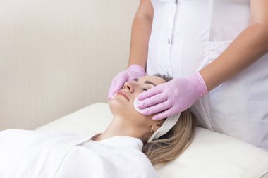 Kozmetoloji. Güzellik salonunda yüzü kapalı genç bir kadının yüz temizleme ameliyatı olurken yakın plan fotoğrafı..