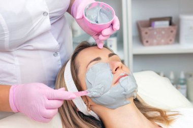 Genç kadın gri aljinat bir maske takıyor. Kozmetik prosedürleri