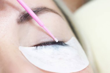 Kirpik uzatma prosedürü. Güzellik salonunda uzun kirpikleri olan güzel bir kadın. Kirpikleri kapat. ellerinizi fırçalayın.