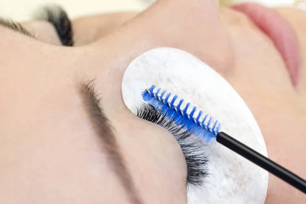 Eyelash extension procedure. Beautiful woman with long eyelashes in a beauty salon. Eyelashes close up. brush in the hands