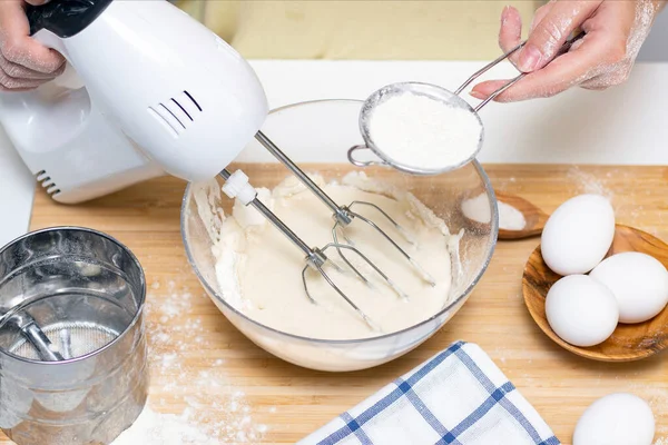 process of making dough for pancakes with ingredients on a light table, eggs and flour are whipped with a mixer