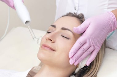 Kozmetik uzmanı genç bir kadının yüzü için nabız prosedürü uyguluyor.. 