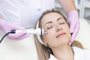 Donanım kozmetolojisi. Kapalı gözlü güzel genç bir kadının güzellik salonunda rf kaldırma prosedürü alırken yakın plan fotoğrafı..