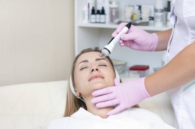 Donanım kozmetolojisi. Kapalı gözlü güzel genç bir kadının güzellik salonunda rf kaldırma prosedürü alırken yakın plan fotoğrafı..