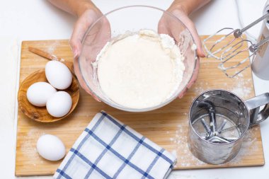 Ekmek ya da ev yapımı hamur işi yapmak. Malzemeler masanın üstünde. Kadın elleri hamuru karıştırmak için mikser tutuyor.