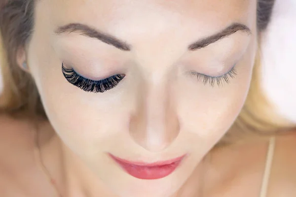 Eyelash extension procedure. Woman eye with long eyelashes. Close up