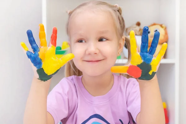 Girl showing painted hands. Hands painted in colorful paints. Education, school, art and painting concept
