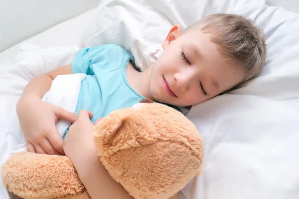 男孩甜美地睡在床上抱着玩具熊 — 图库照片
