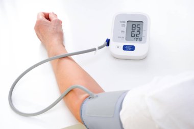 Adult woman measures blood pressure, white background. arterial hypotension.