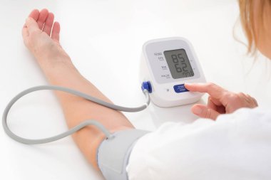Adult woman measures blood pressure, white background. arterial hypotension.