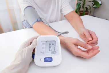 doctor in gloves measures blood pressure to a person, white background. arterial hypotension. hand and tonometer close up.