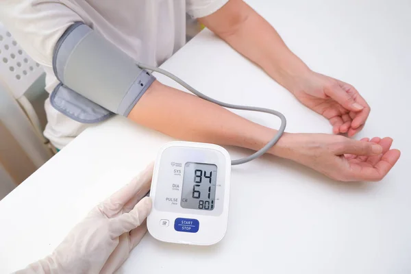 doctor in gloves measures blood pressure to a person, white background. arterial hypotension. hand and tonometer close up.
