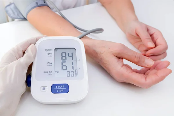 doctor in gloves measures blood pressure to a person, white background. arterial hypotension. hand and tonometer close up.