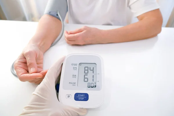 doctor in gloves measures blood pressure to a person, white background. arterial hypotension. hand and tonometer close up.