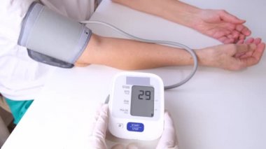 doctor in gloves measures blood pressure to a person, white background. arterial hypotension. hand and tonometer close up.