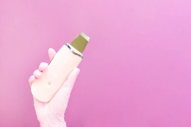 Kozmetik konsepti, kozmetik uzmanı ultrasonik, pembe arka plan. ultrasonik yüz temizleyici