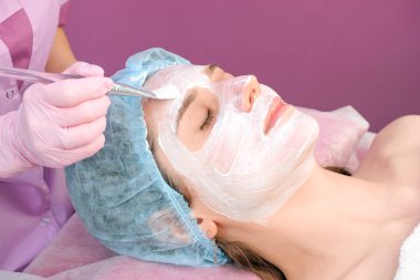 Salonda yüzünde temizlik maskesi olan genç bir kadın. Soyulma işlemi