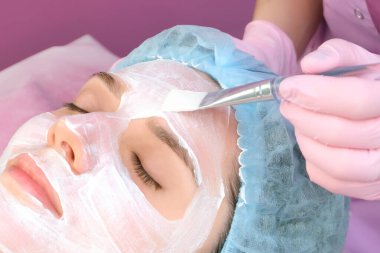 Salonda yüzünde temizlik maskesi olan genç bir kadın. Soyulma işlemi