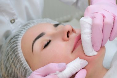 Kozmetoloji. Güzellik salonunda yüzü kapalı genç bir kadının yüz temizleme ameliyatı olurken yakın plan fotoğrafı..