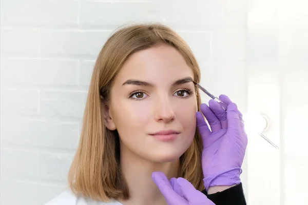 Young woman shaping eyebrows with brush, close up