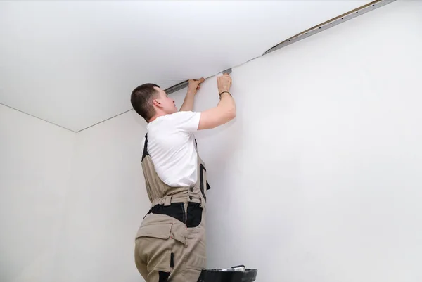 worker installs a stretch ceiling. Construction and renovation concept