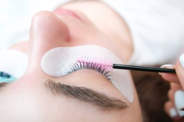 Bir güzellik salonunda kirpik temizleme işlemi yapan genç bir kadın.