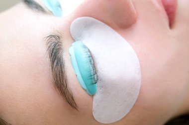 Bir güzellik salonunda kirpik temizleme işlemi yapan genç bir kadın.