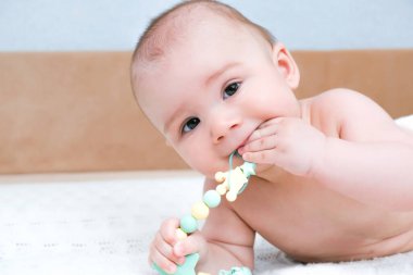 Bebek süt dişleri patlıyor, diş etleri kaşınıyor. Çocuğun ağzında oyuncak var.