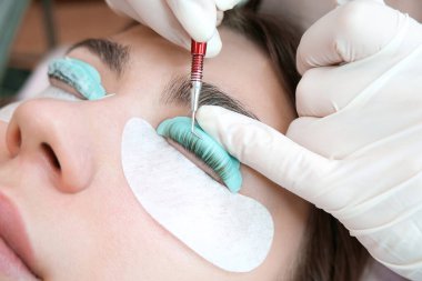 Bir güzellik salonunda kirpik temizleme işlemi yapan genç bir kadın.