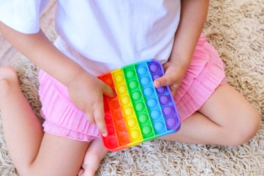 Tatlı suratsız çocuk Pop It 'le oynuyor. Popo kabarcığı esnek, duyusal oyuncağı itin, boşaltın ve çocuğun gelişmesine yardımcı olun.