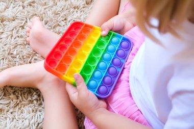 Çocuk kanat çırpan bir hareketle oynuyor. Popüler çocuklar esnek duyusal oyuncaklar iyi motor beceriler geliştirir, anti-stres, otistik insanlarla eğitim için kullanılabilir, popit oyuncak