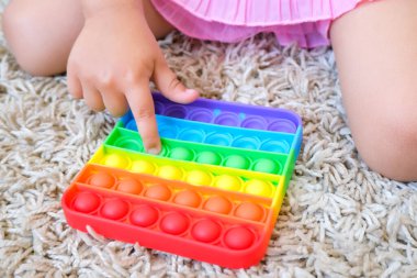 Tatlı suratsız çocuk Pop It 'le oynuyor. Popo kabarcığı esnek, duyusal oyuncağı itin, boşaltın ve çocuğun gelişmesine yardımcı olun.