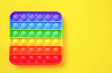 Gökkuşağı oyuncak hareketini boş fotokopi alanının arka planında yap. sarı arkaplan