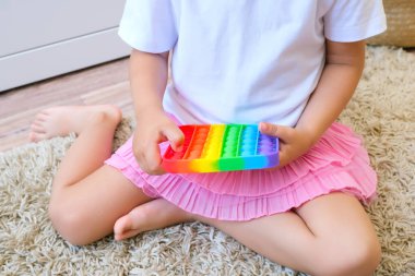 Tatlı suratsız çocuk Pop It 'le oynuyor. Popo kabarcığı esnek, duyusal oyuncağı itin, boşaltın ve çocuğun gelişmesine yardımcı olun.