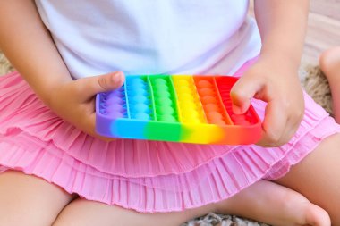 Tatlı suratsız çocuk Pop It 'le oynuyor. Popo kabarcığı esnek, duyusal oyuncağı itin, boşaltın ve çocuğun gelişmesine yardımcı olun.