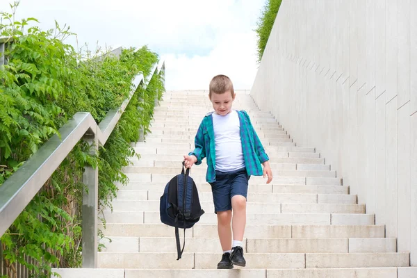 学校への道を通りに彼の手の中にリュックを持つ学校の少年は階段を下ります 学校に戻る — ストック写真