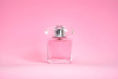 Pembe pastel arka planda zarif bir parfüm şişesi.