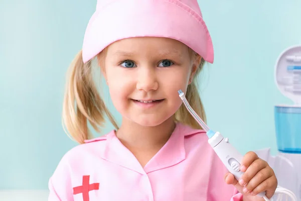 Una Niñita Con Vestido Enfermera Cepilla Los Dientes Con Irrigador —  Fotos de Stock