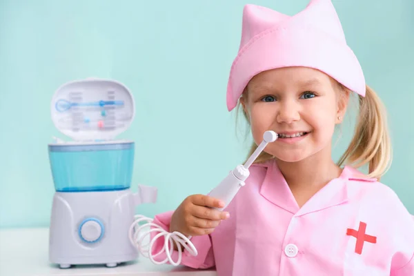 Una Niñita Con Vestido Enfermera Cepilla Los Dientes Con Irrigador —  Fotos de Stock