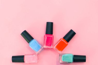 Pembe arka planda çok renkli tırnak cilası. Manikür kavramı