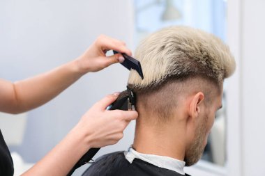 Berber salonundaki koltukta saç makasıyla sarışın bir gencin saç kesimi, erkekler ve erkekler için berber dükkanı konsepti.