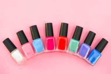 Pembe arka planda çok renkli tırnak cilası. Manikür kavramı